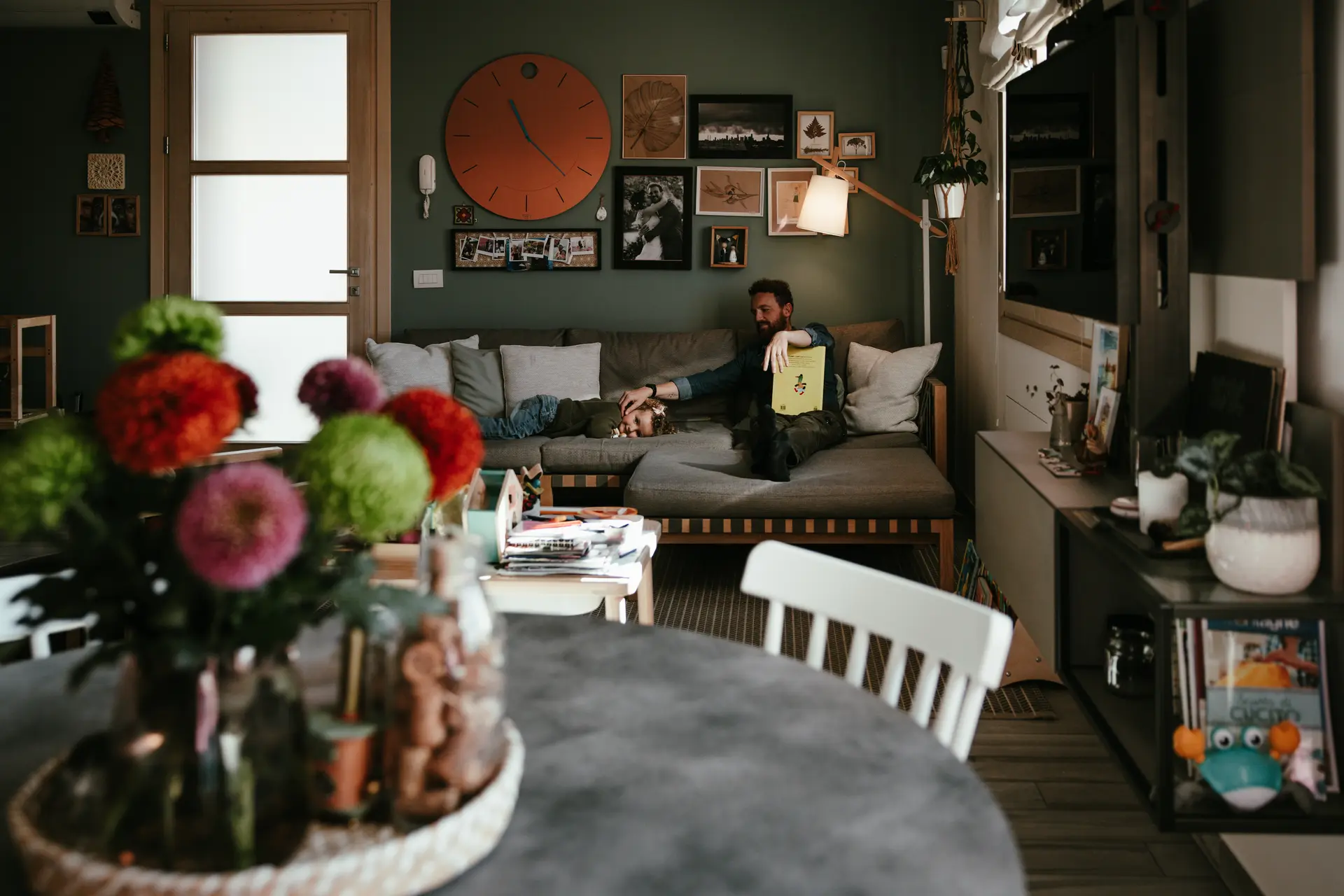 Padre e figlia che leggono un libro sul divano in un salotto accogliente – Fotografia lifestyle di Sara Mellerio Famiglia