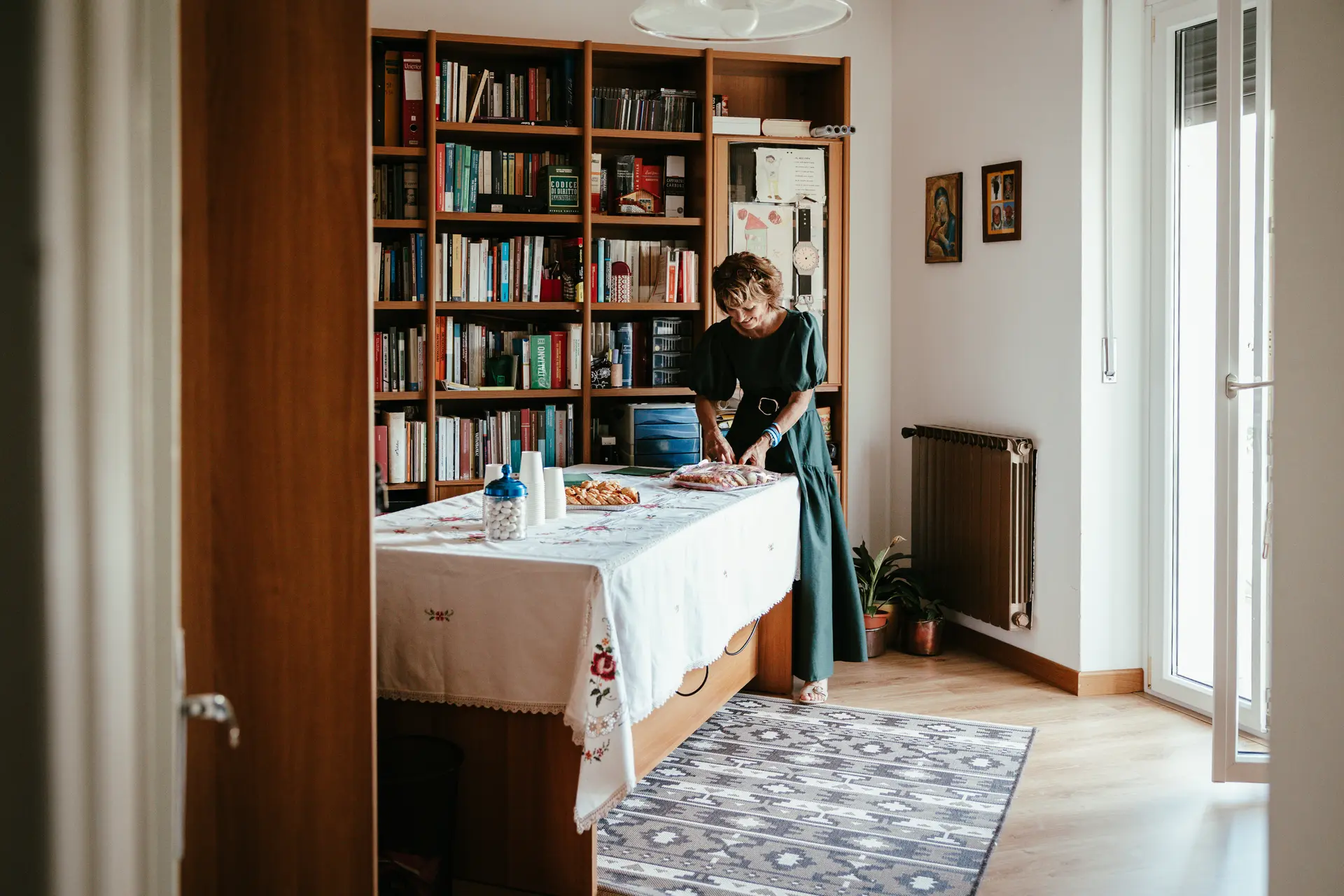 Preparativi del matrimonio in casa, donna che allestisce la tavola per il rinfresco catturata da Sara Mellerio.