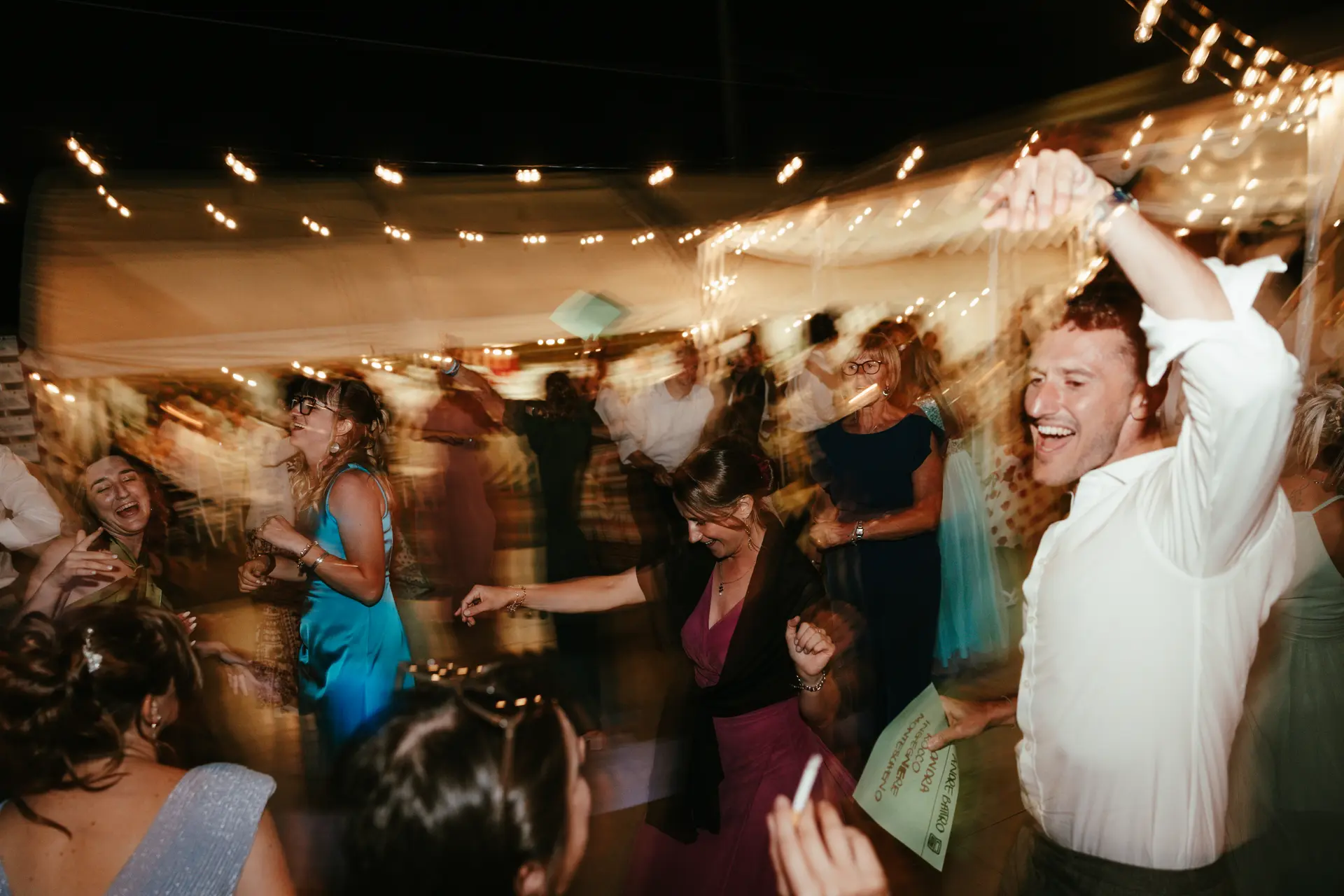 Balli scatenati e atmosfera di festa durante il ricevimento nuziale serale, fotografia dinamica di Sara Mellerio.