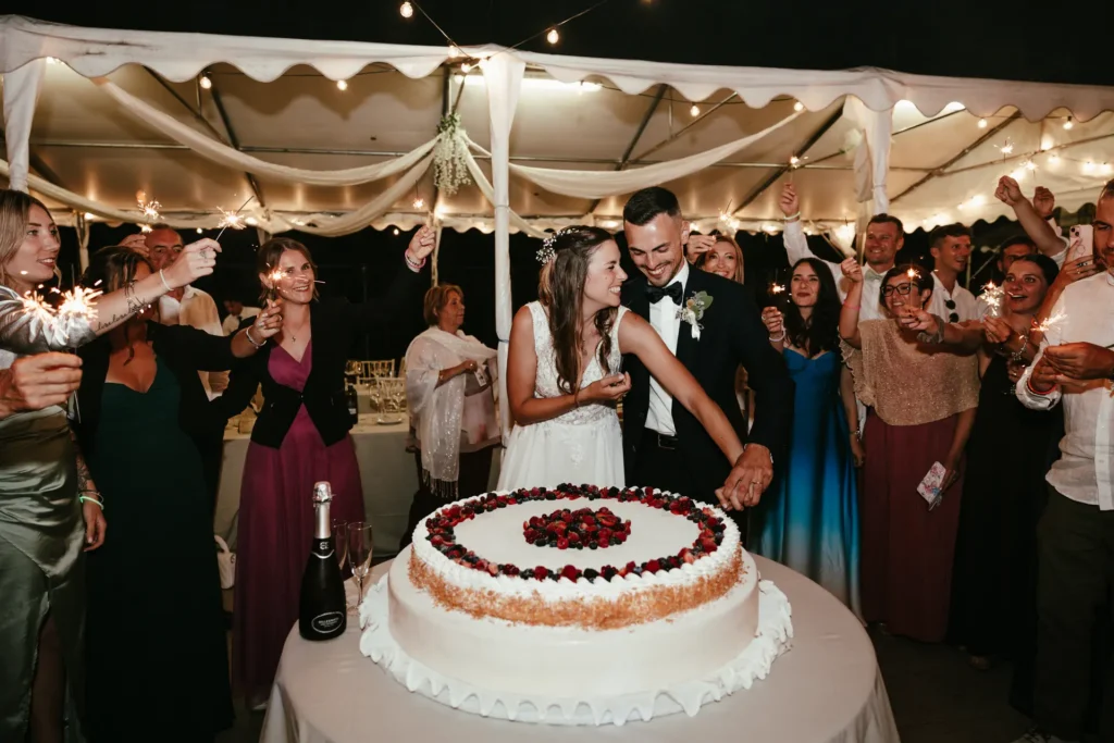 matrimoni-03-26-16 Sposi sorridenti mentre tagliano la torta nuziale decorata con frutti di bosco tra fontane di luce, Sara Mellerio.