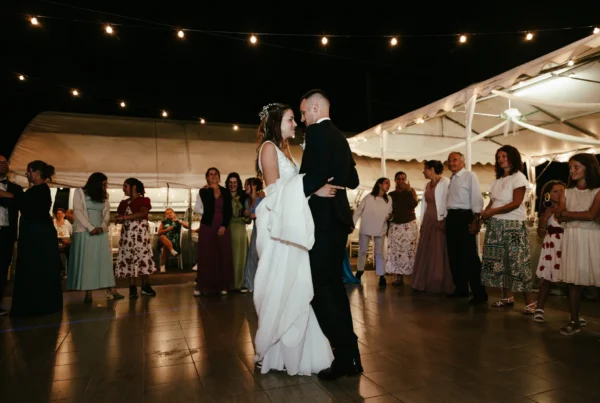 Primo ballo degli sposi sotto filari di luci in una location per matrimoni all'aperto, fotografia serale di Sara Mellerio.