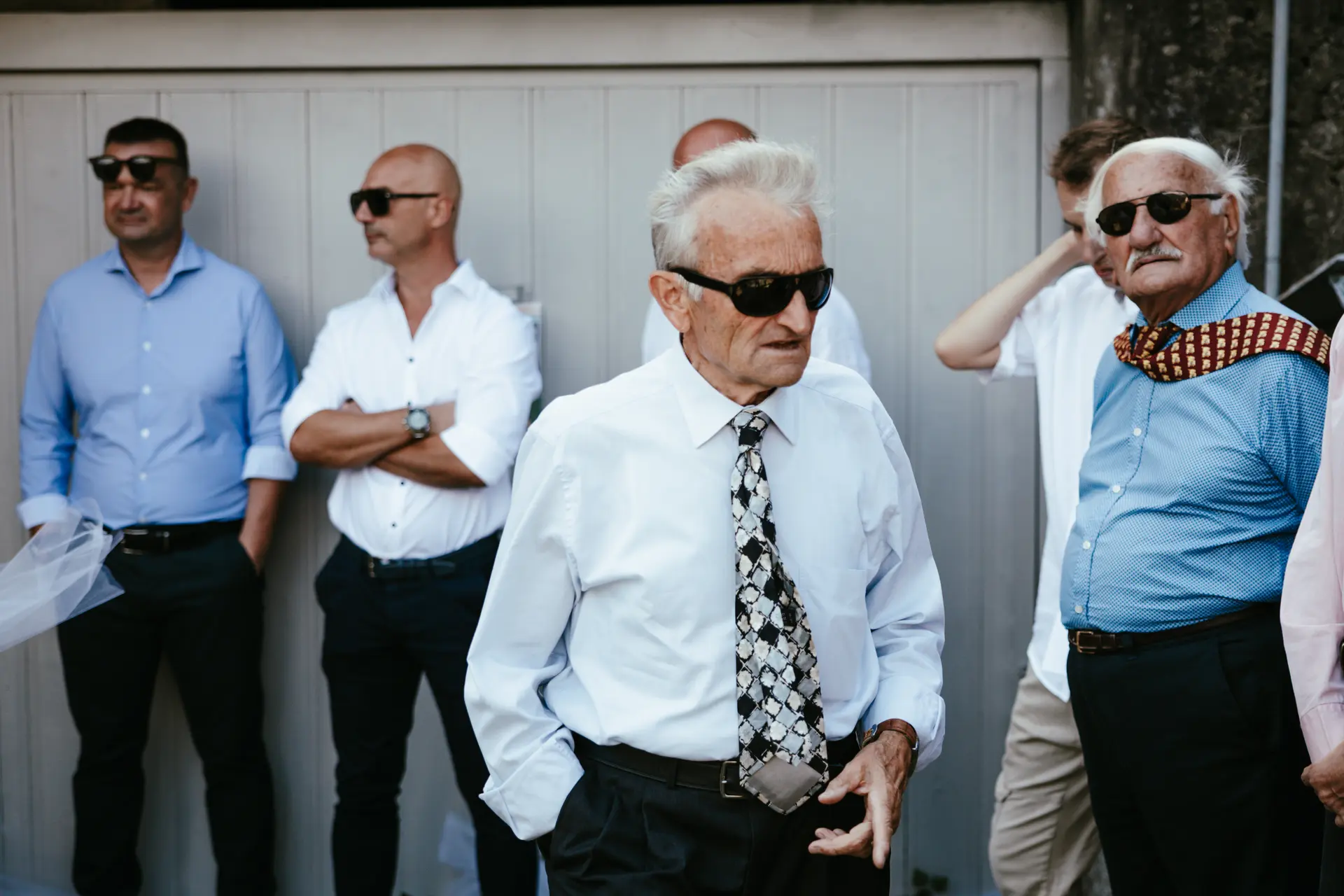 Invitati al matrimonio con occhiali da sole e abiti eleganti, fotografia di reportage di nozze di Sara Mellerio.