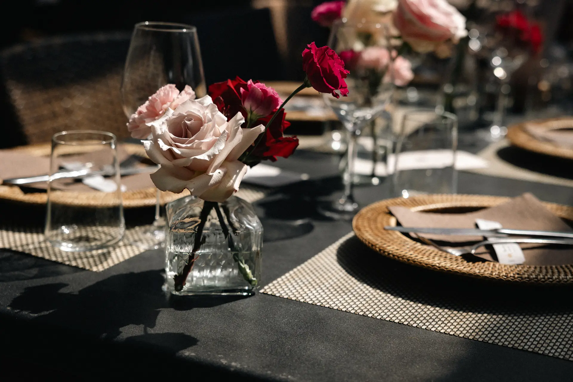Dettaglio centrotavola con rose rosa e rosse in un vaso di vetro, fotografia di dettagli per matrimoni di Sara Mellerio.
