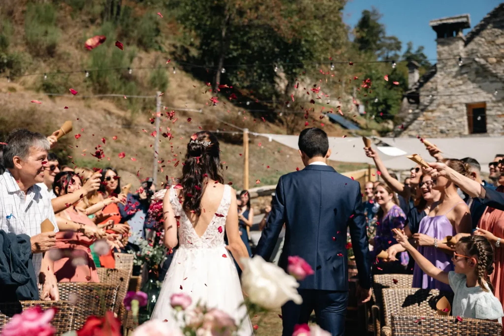 matrimoni-03-26-5 Sposi che camminano tra una pioggia di petali rossi dopo la cerimonia all'aperto, scatto emozionale di Sara Mellerio.