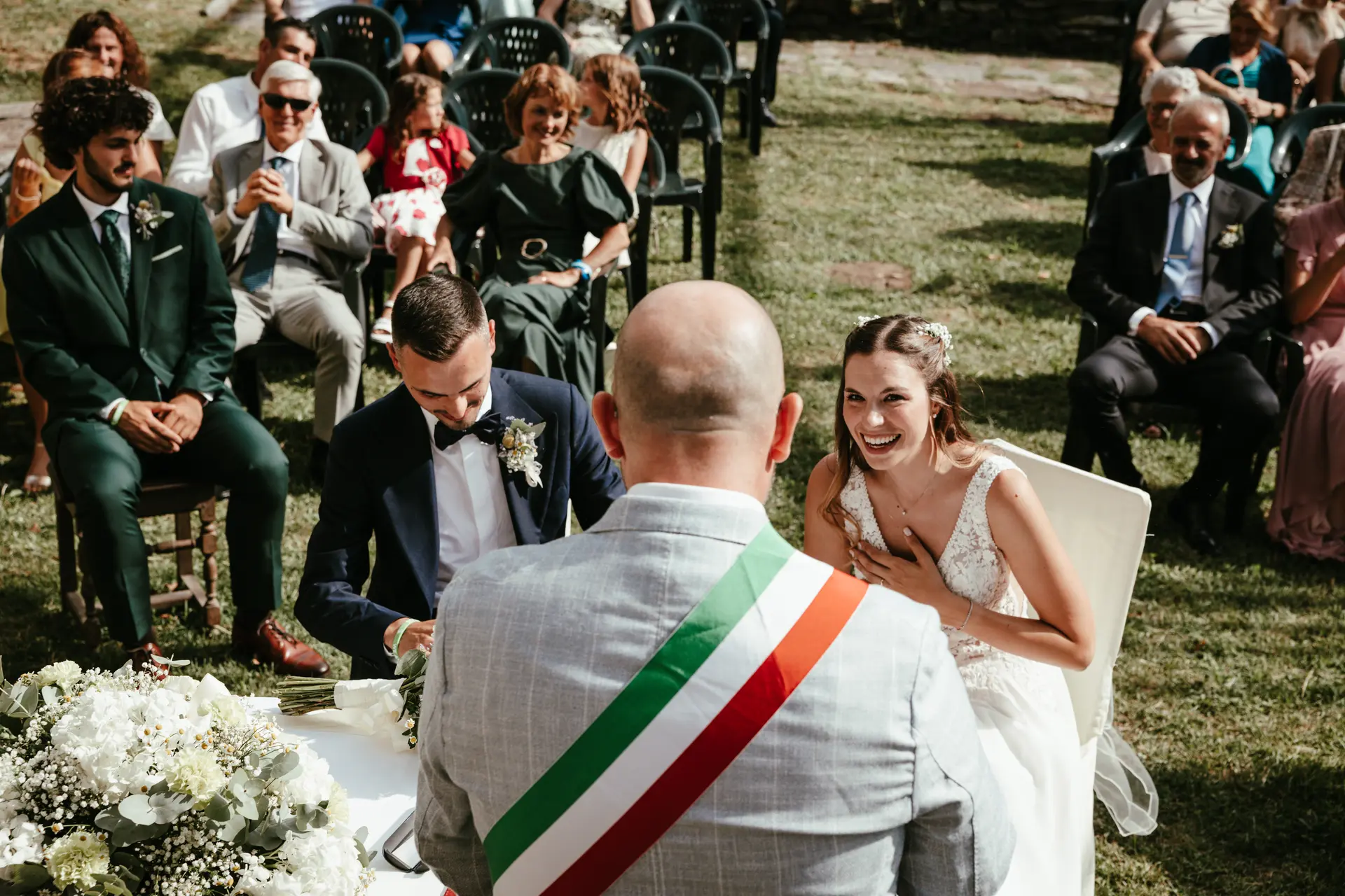 La sposa ride felice durante la cerimonia civile celebrata all'aperto, fotografia spontanea di matrimonio di Sara Mellerio.